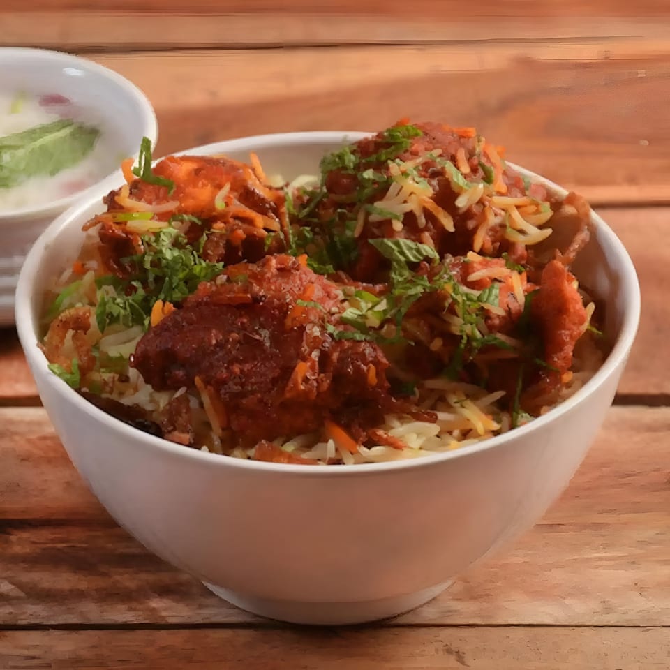 Aachi Biryani's chicken biryani, topped with fresh cilantro, served in a white bowl on a wooden table.