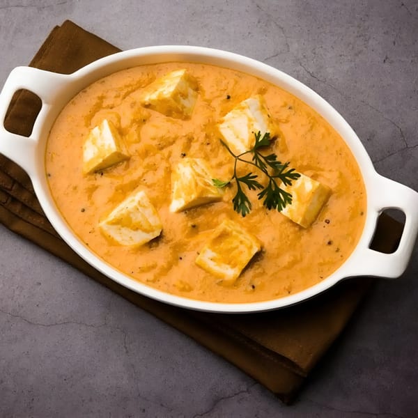 Aachi Biryani's paneer butter masala, a creamy orange curry with paneer cubes and cilantro in a white dish.