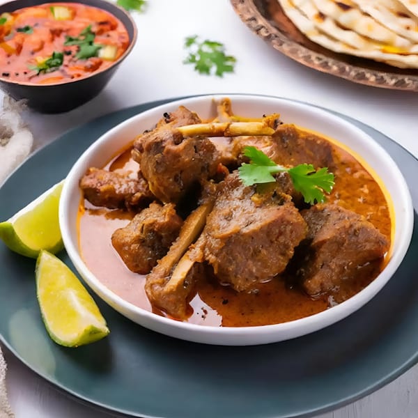 Aachi Biryani's Indian lamb curry with lime wedges, a side of red curry, and naan bread.