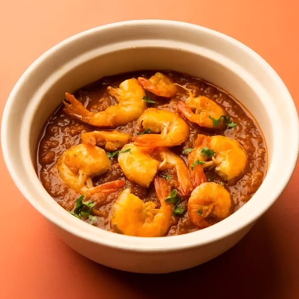 Aachi Biryani's Indian shrimp curry, garnished with fresh herbs, served in a white bowl.