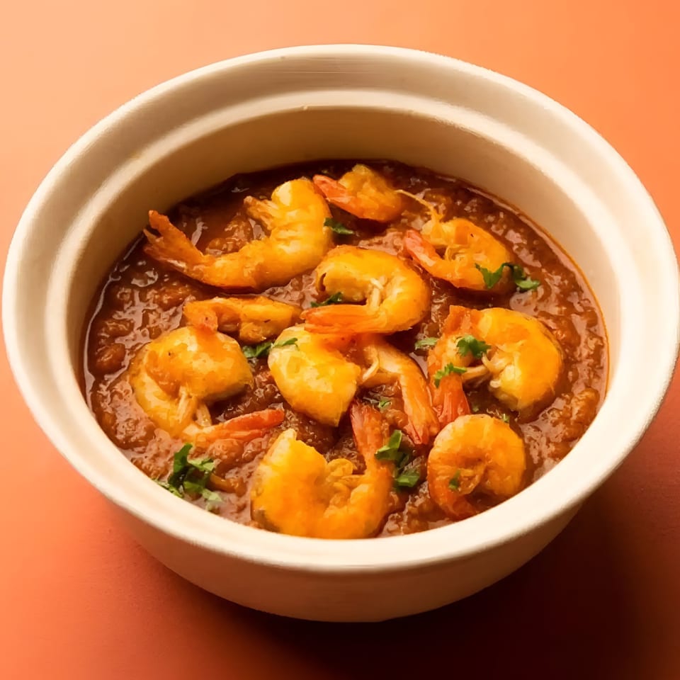 Aachi Biryani's Indian shrimp curry, garnished with fresh herbs, served in a white bowl.